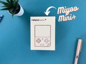 Consola portátil retro Miyoo Mini+ na sua caixa sobre um fundo azul