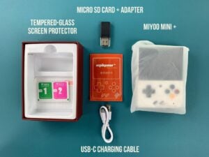 Der Inhalt der Miyoo Mini+ Retro-Box vor blauem Hintergrund