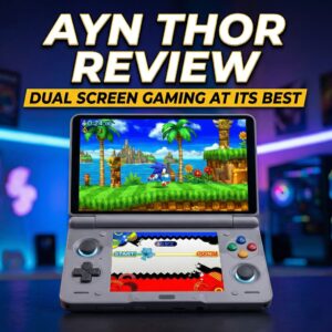 The image features a dual-screen, clamshell-style handheld gaming device centered on a dark surface against a blurred, neon-lit gaming room background. The device is grey with colorful "ABXY" buttons and glowing blue rings around the joysticks. The top screen displays a vibrant 3D Sonic the Hedgehog game, while the bottom screen shows a stylized menu or secondary game interface.The image features a dual-screen, clamshell-style handheld gaming device centered on a dark surface against a blurred, neon-lit gaming room background. The device is grey with colorful "ABXY" buttons and glowing blue rings around the joysticks. The top screen displays a vibrant 3D Sonic the Hedgehog game, while the bottom screen shows a stylized menu or secondary game interface.