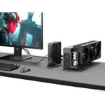 GPD G2 eGPU enclosure connected to a GPD mini PC and gaming monitor, powering a high-end AAA game with a triple-fan graphics card.